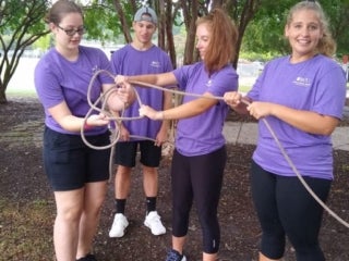 A group of students attempt to accomplish tasks with a rope