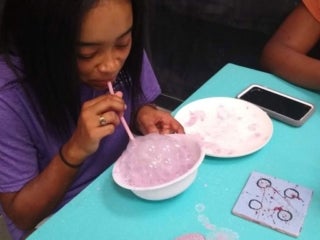 A student blowing bubbles in a bowl