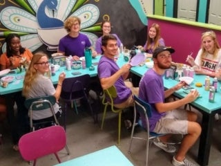 a group of students sitting around a corner table performing crafting