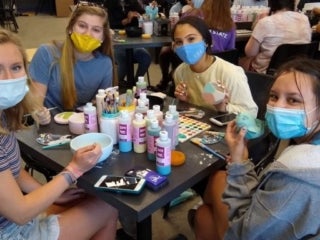 Students wearing masks sitting around the crafting table