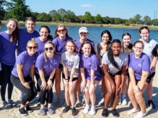 Students standing on the sand in front of a lake