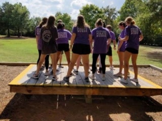 a group of student standing on a wooden deck