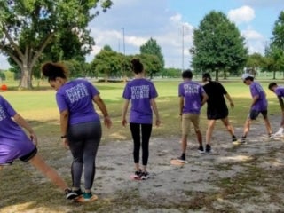 students in a linear formation taking turn standing on round color shapes