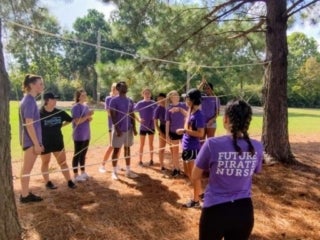 a group of students standing in front of a rope course