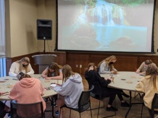 students sitting around two round tables writing