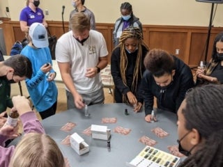 Students standing around a round table looking at vials