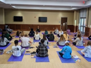 Students sitting on yoga mats in a studio
